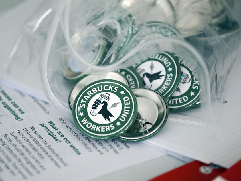 caption: Pro-union pins sit on a table during a watch party for Starbucks' employees union election in December in Buffalo, N.Y. Starbucks union organizers say the company is closing a New York store to retaliate.