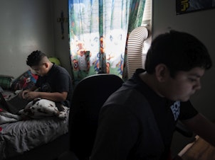 caption: Eloyd Castro, 11, izquierda, juega videojuegos con su hermano Emmanuel Castro, 12, derecha, en su casa en Uvalde, Texas.