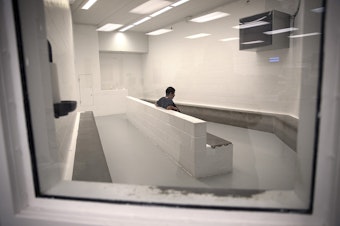 caption: A detainee sits in the intake area at the Tacoma Detention Center in 2017.