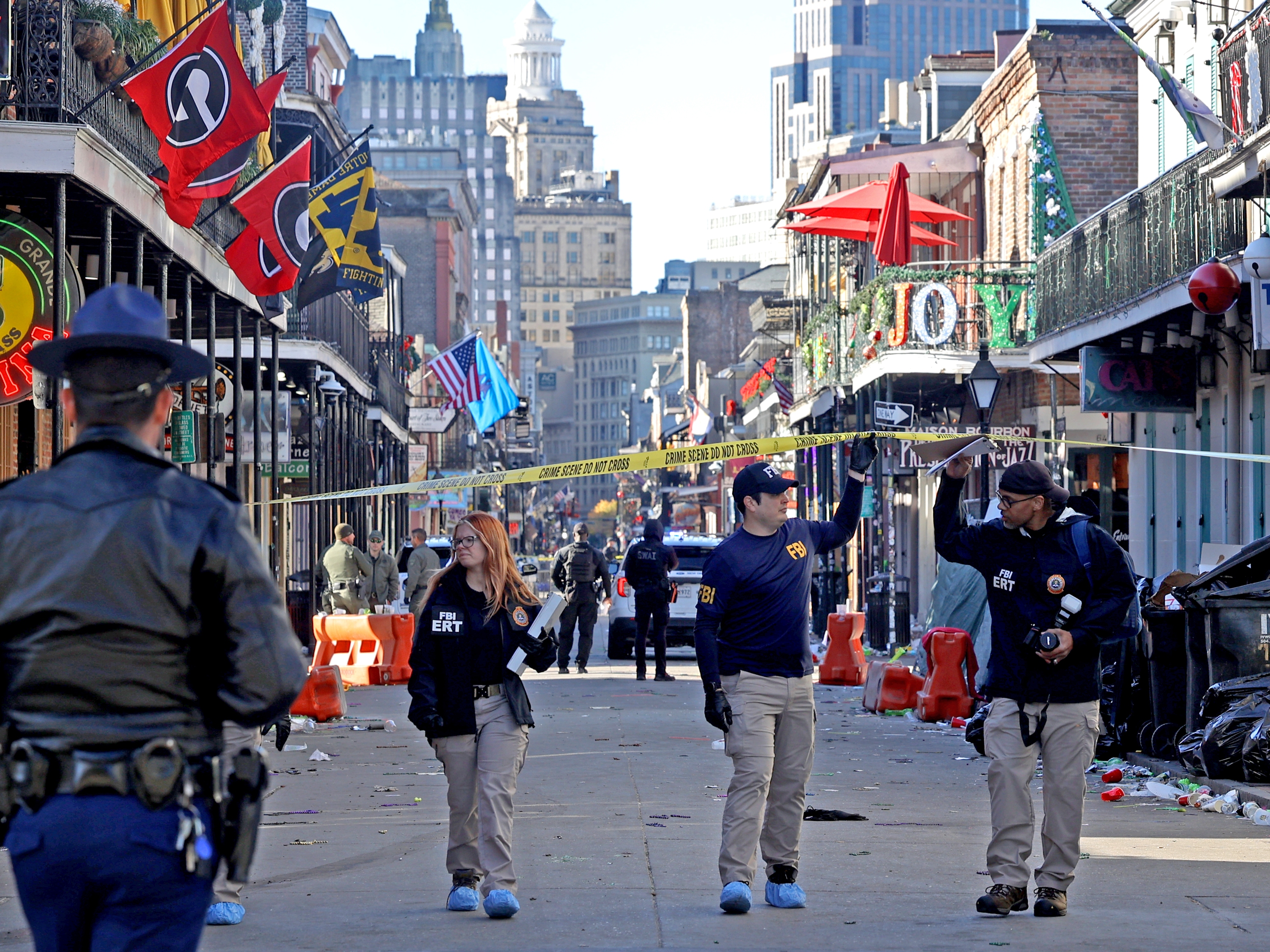 caption: Law enforcement officers from multiple agencies work the scene on Bourbon Street after a person drove a truck into the crowd.