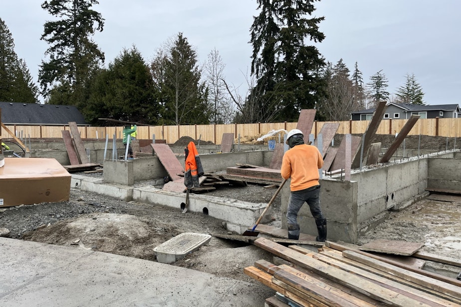 caption: Workers prepare foundations for more new townhomes at the Braes Park housing development in Edmonds