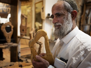 caption: Itay Levy makes music and Kinnors — intricately-carved wooden harps.