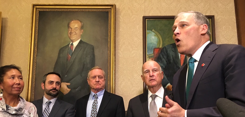 Gov. Jay Inslee speaks about climate change in the foyer of his office. On his right is former California Gov. Jerry Brown and state lawmakers