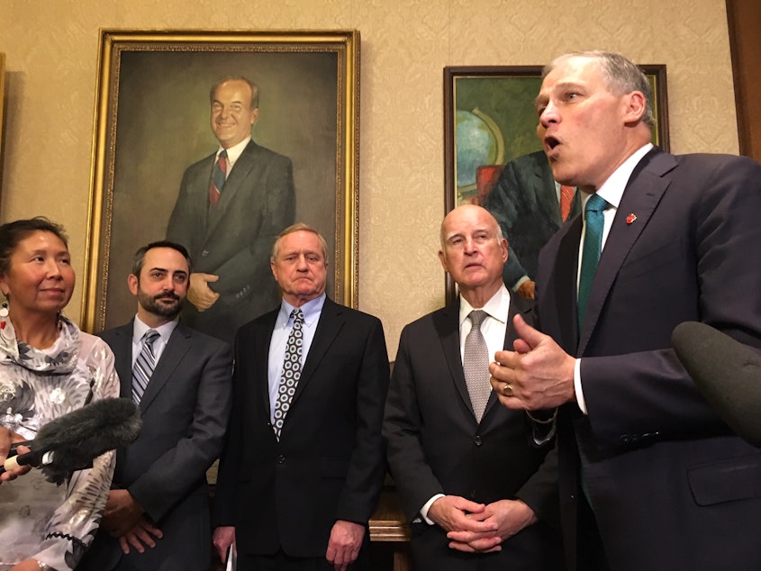 caption: Gov. Jay Inslee speaks about climate change in the foyer of his office. On his right is former California Gov. Jerry Brown and state lawmakers