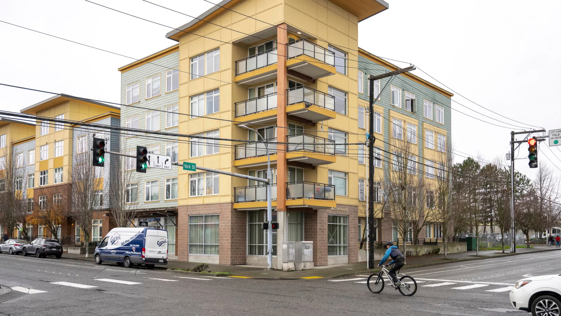 caption: A cyclist passes by the apartment building in Bellingham, Wash. on December 3. Suspected shooter Rahmanullah Lakanwal lived there with his family and the building was raided by FBI agents in the hours after the National Guard attack in Washington, D.C. on Nov. 26, 2025.

