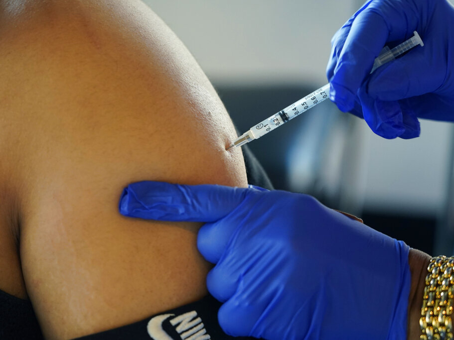 caption: A Jackson, Miss., resident receives a Pfizer booster shot from a nurse at a vaccination site Feb. 8.