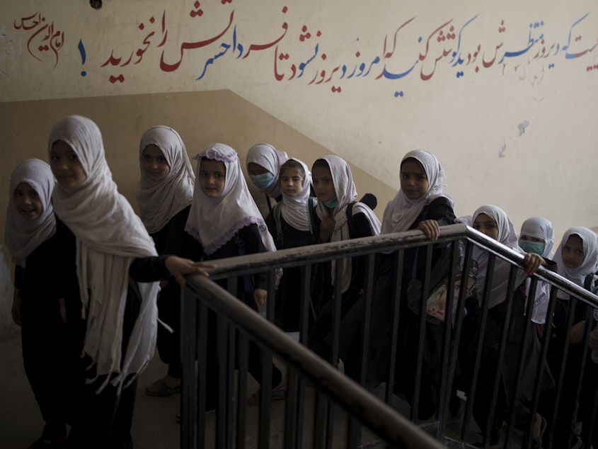 caption: Girls enter a school before class in Kabul on Sept. 12, 2021. In a surprise decision, the hardline leadership of Afghanistan's new rulers has decided against opening educational institutions to girls beyond sixth grade.