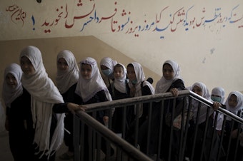 caption: Girls enter a school before class in Kabul on Sept. 12, 2021. In a surprise decision, the hardline leadership of Afghanistan's new rulers has decided against opening educational institutions to girls beyond sixth grade.
