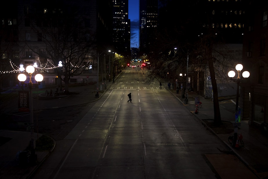 caption: A pedestrian crosses an empty 4th Avenue on Wednesday, March 25, 2020, in Seattle.