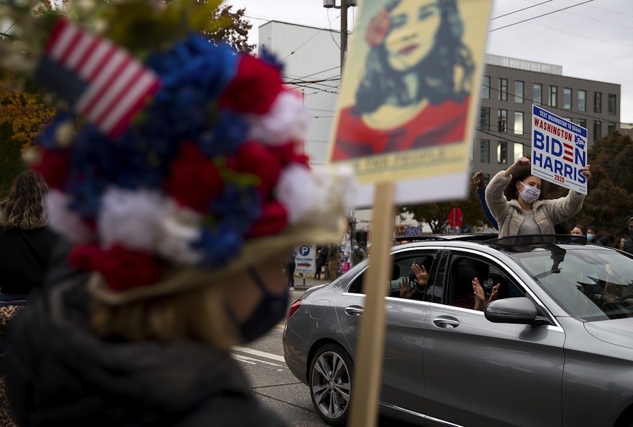 caption: Oksana Reva stands out of a sun roof while holding a Biden-Harris sign during a celebration after Joe Biden was officially named the president elect on Saturday, November 7, 2020, at the intersection of 10th Avenue and East Pine Street in Seattle.