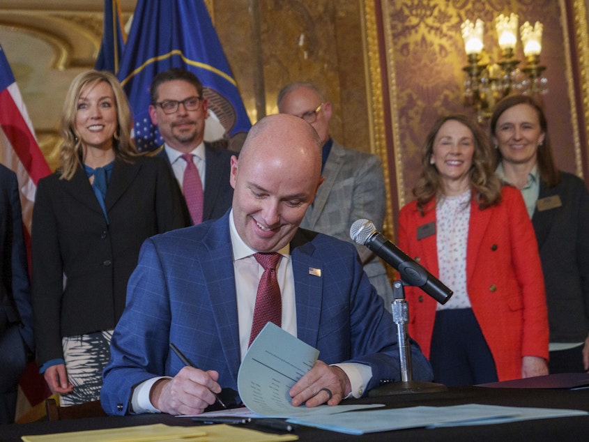 caption: Gov. Spencer Cox signs two social media regulation bills during a ceremony at the Capitol building in Salt Lake City on Thursday, March 23, 2023. Cox signed a pair of measures that aim to limit when and where children can use social media and stop companies from luring kids to the sites.