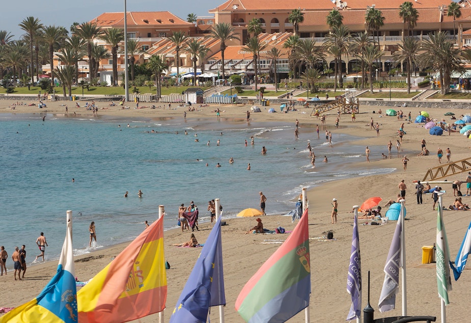 caption: Tourists enjoy a day at the beach on the Canary Island of Tenerife. A Welsh recruitment company is treating its entire staff to a vacation on the island.