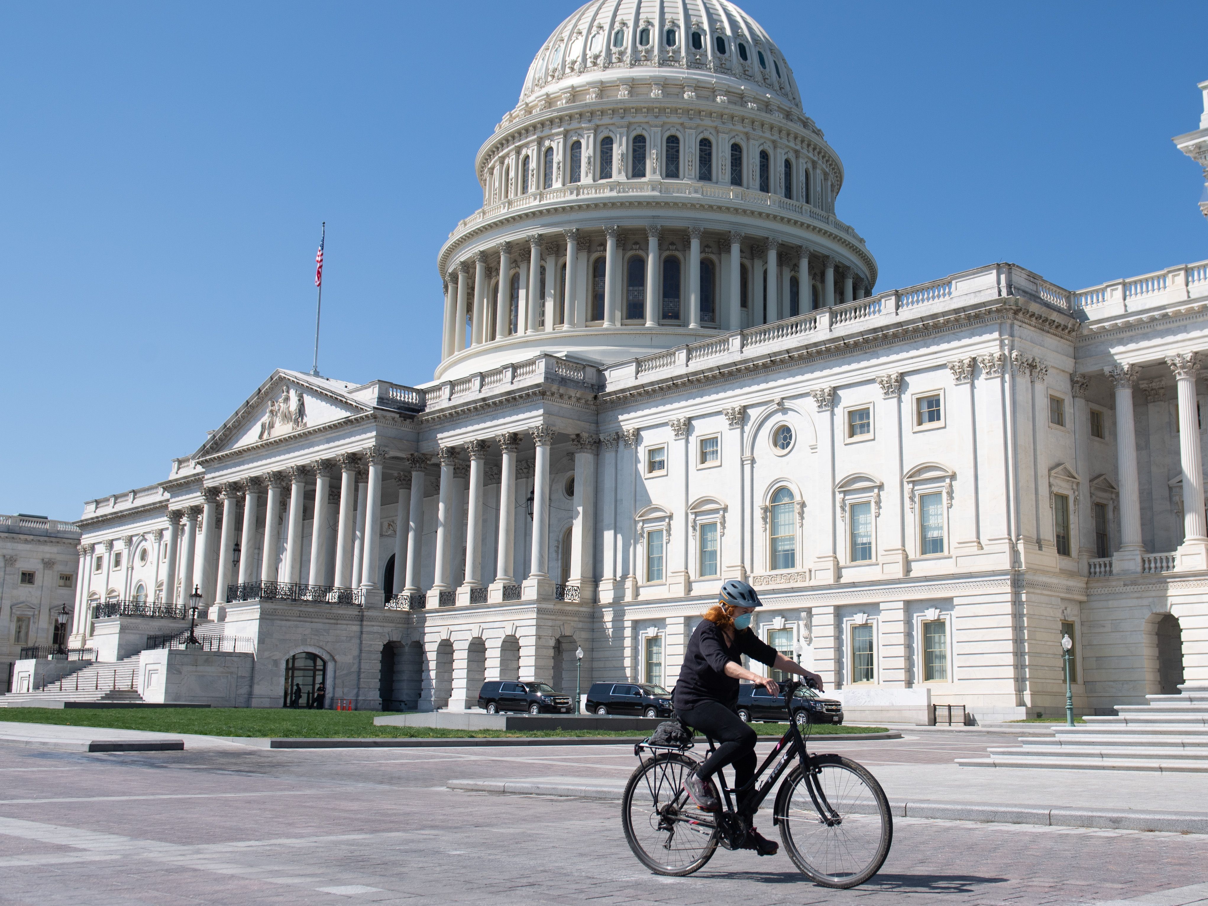 A woman wearing a mask to prevent the spread of the coronavirus rides a bike in front of the U.S. Capitol in Washington, D.C., on April 9.