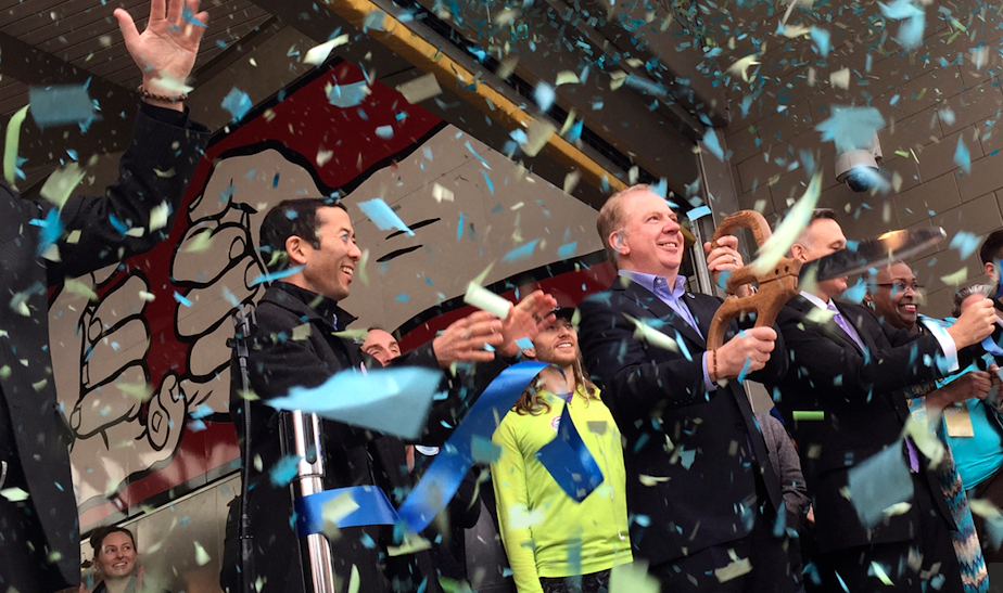 caption: Seattle Mayor Ed Murray (holding giant scissors) and other officials celebrate the opening of a light-rail station on Capitol Hill.