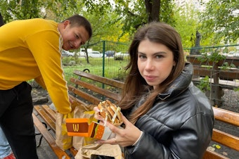 caption: Yaroslav Holovatenko (left) and a friend with their McDonald's meals in Kyiv on Wednesday.