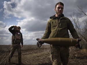 caption: Ukrainian soldiers carry shells to fire at Russian positions on the front line, near the city of Bakhmut, in Ukraine's Donetsk region, on March 25. The outgunned and outnumbered Ukrainian troops have been struggling to halt Russian advances.