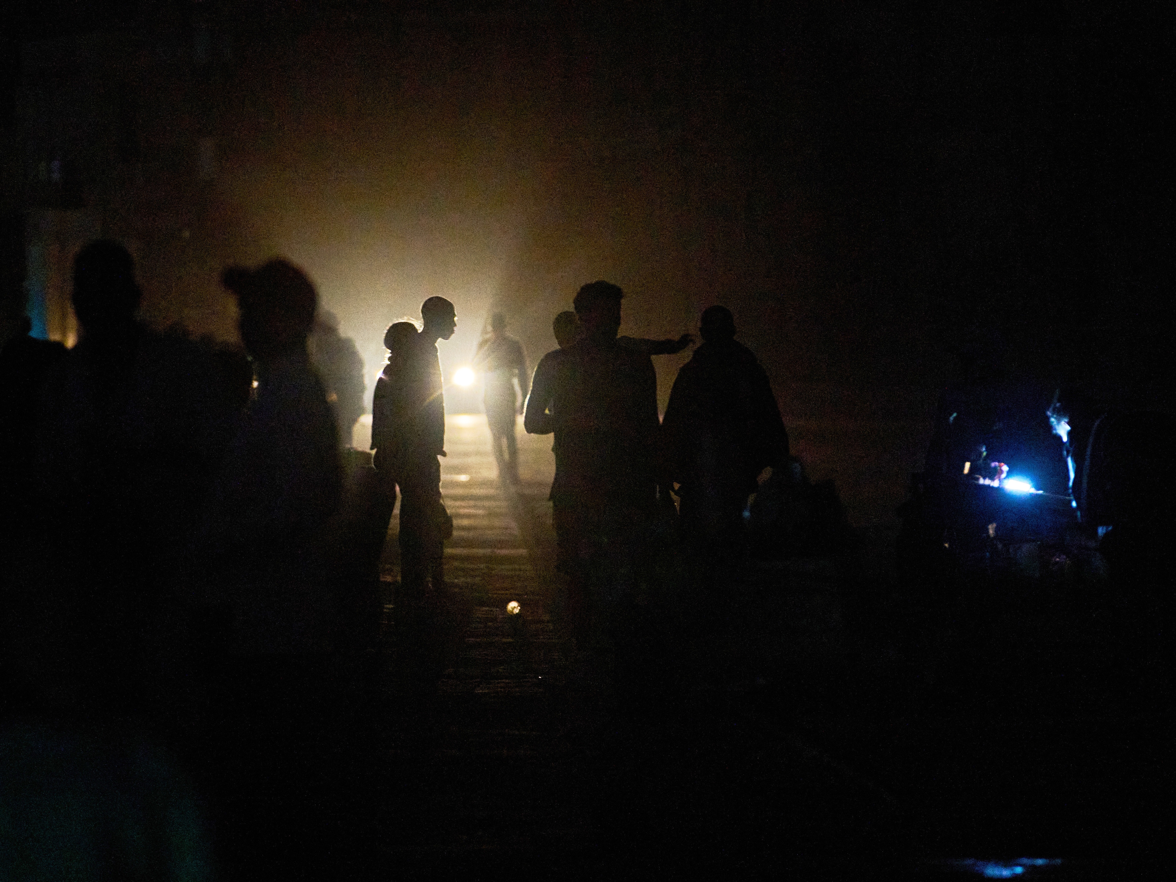 caption: People walk on a street in the dark during a blackout in Havana, Cuba, Saturday, March 21, 2026.