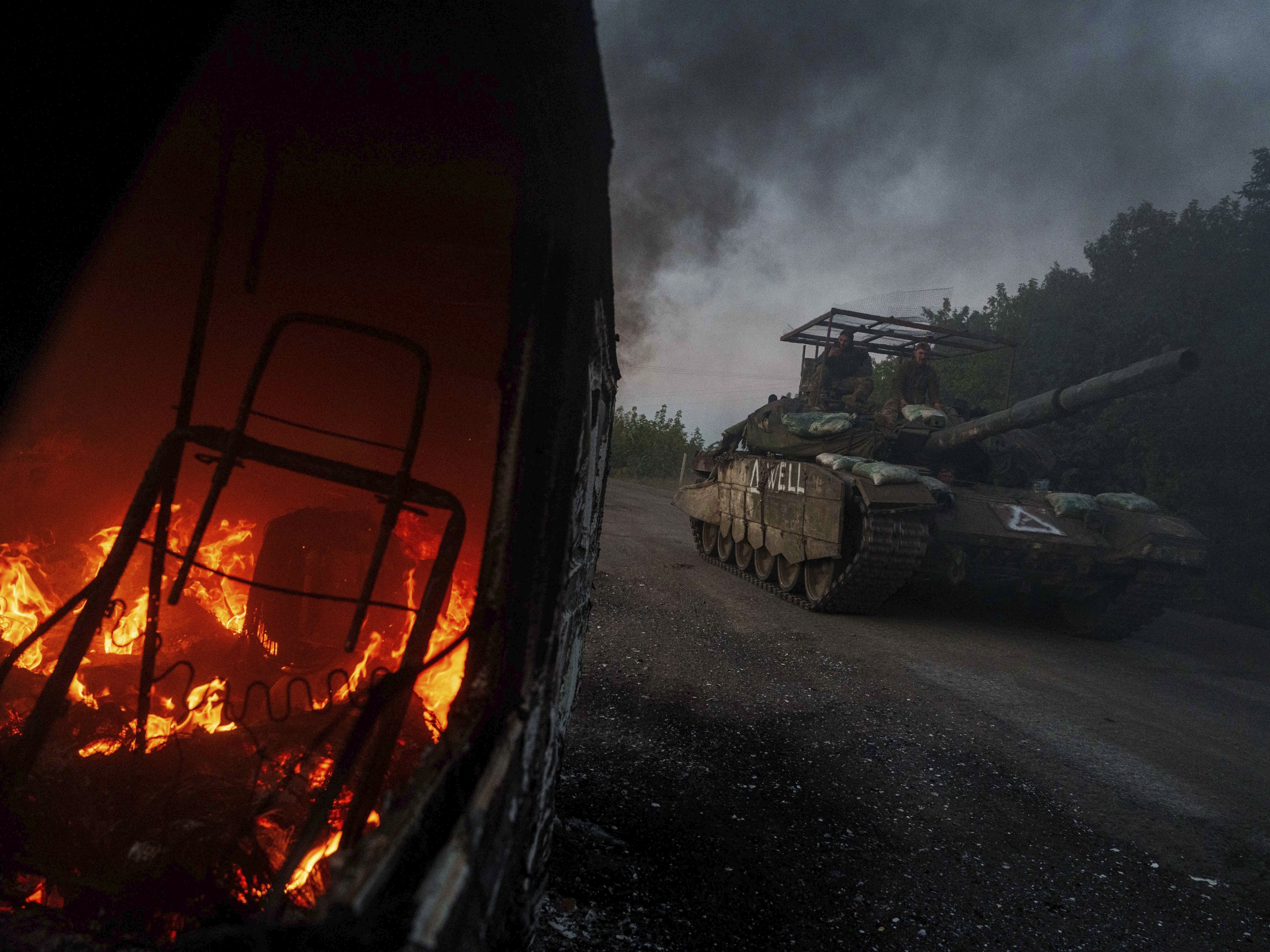 caption: A Ukrainian tank passes by a burning car near the Russian-Ukrainian border, Sumy region, Ukraine, on Aug. 14, 2024.