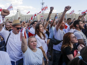 caption: People with old Belarusian national flags shout during an opposition rally in August in Minsk, Belarus.