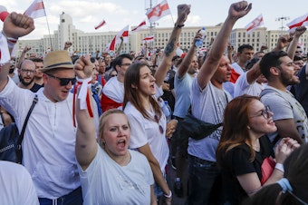 caption: People with old Belarusian national flags shout during an opposition rally in August in Minsk, Belarus.