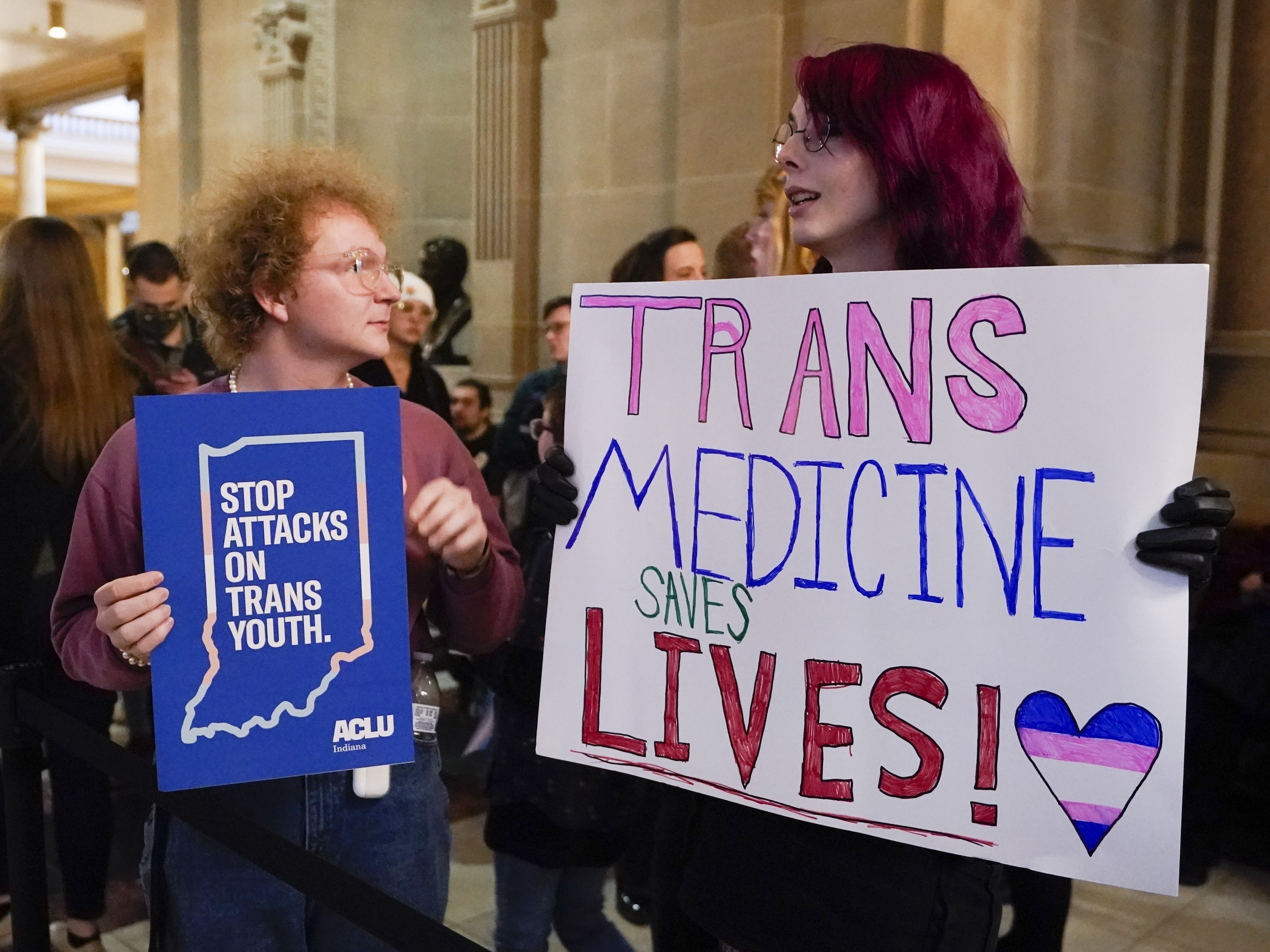 caption: Protesters stand outside of the Senate chamber at the Indiana Statehouse on Feb. 22, 2023, in Indianapolis. Republican Governors in Indiana and Idaho have signed into law bills banning gender-affirming care for minors early April 2023, making those states the latest to prohibit transgender health care this year.