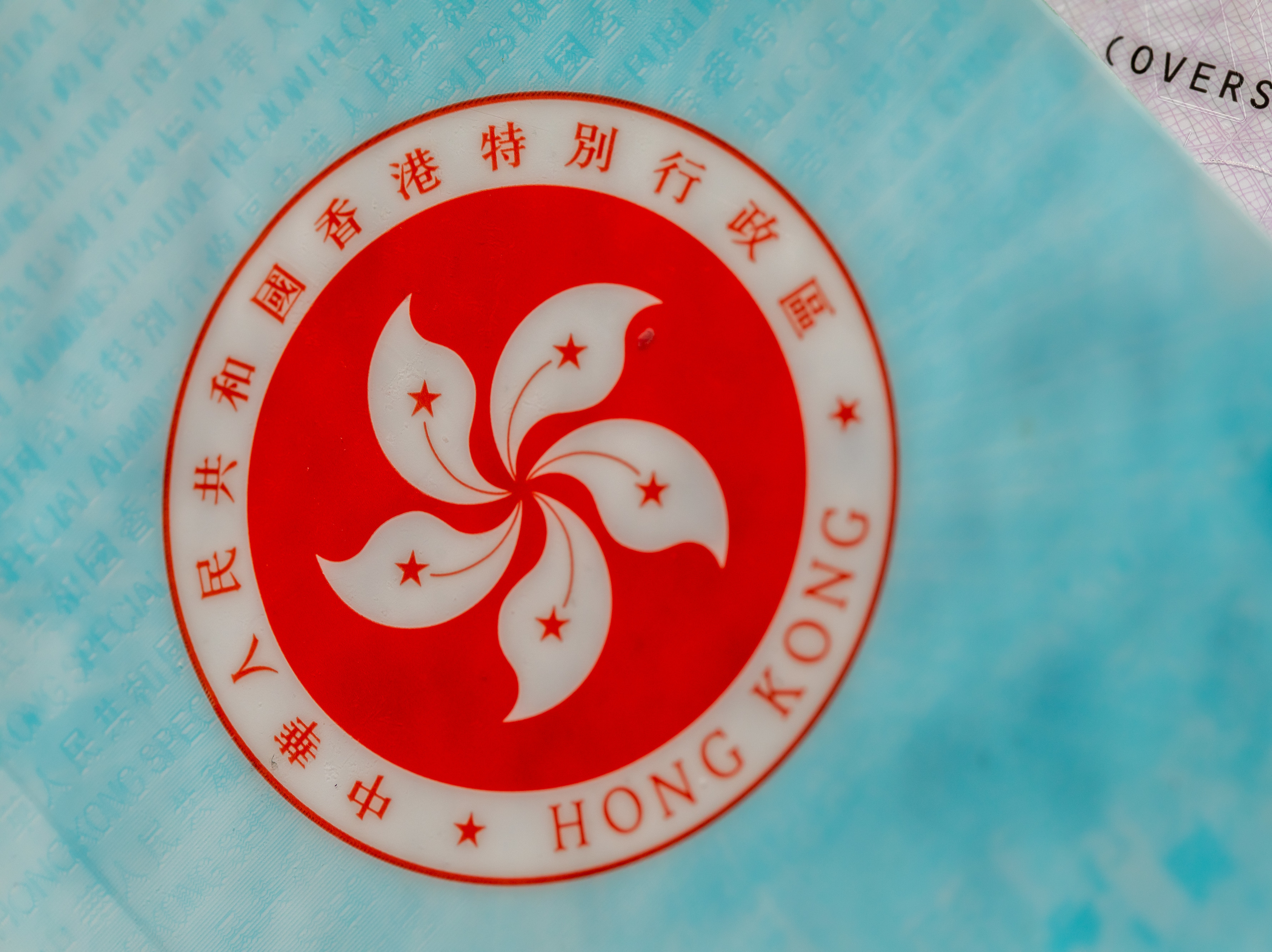 caption: The Hong Kong Special Administrative Region (HKSAR) emblem on a page of the HKSAR passport arranged in Hong Kong, China, earlier this year. The Biden administration says it will allow Hong Kong residents to remain and work in the U.S. for at least 18 months without fear of deportation.