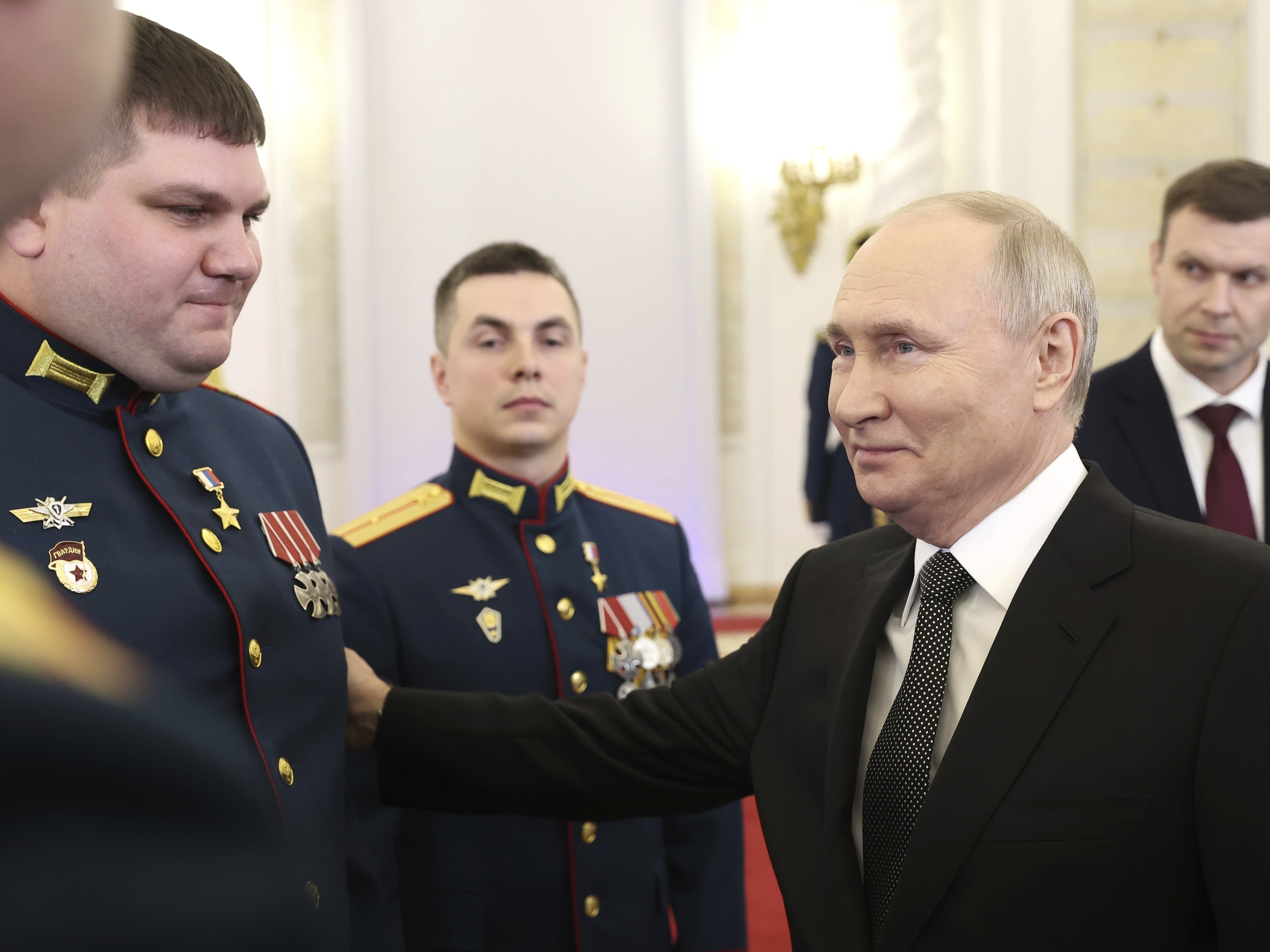 caption: Russian President Vladimir Putin talks with awarded Russian servicemen at the Grand Kremlin Palace in Moscow on Friday.