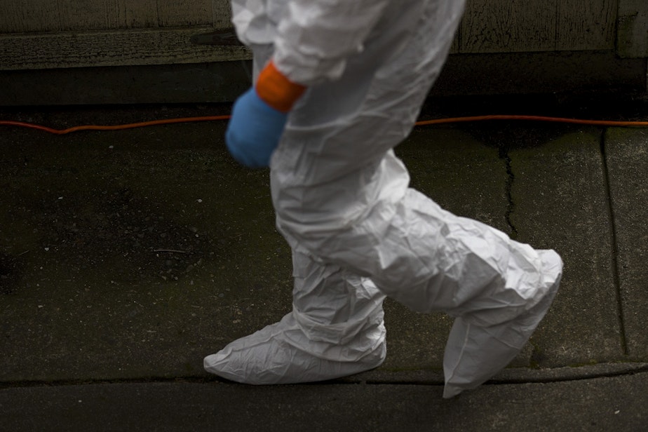 caption: A member of a Servpro cleaning crew walks into the Life Care Center of Kirkland, the long-term care facility at the epicenter of the coronavirus outbreak in Washington state, to clean the interior of the facility, on Wednesday, March 11, 2020, in Kirkland.