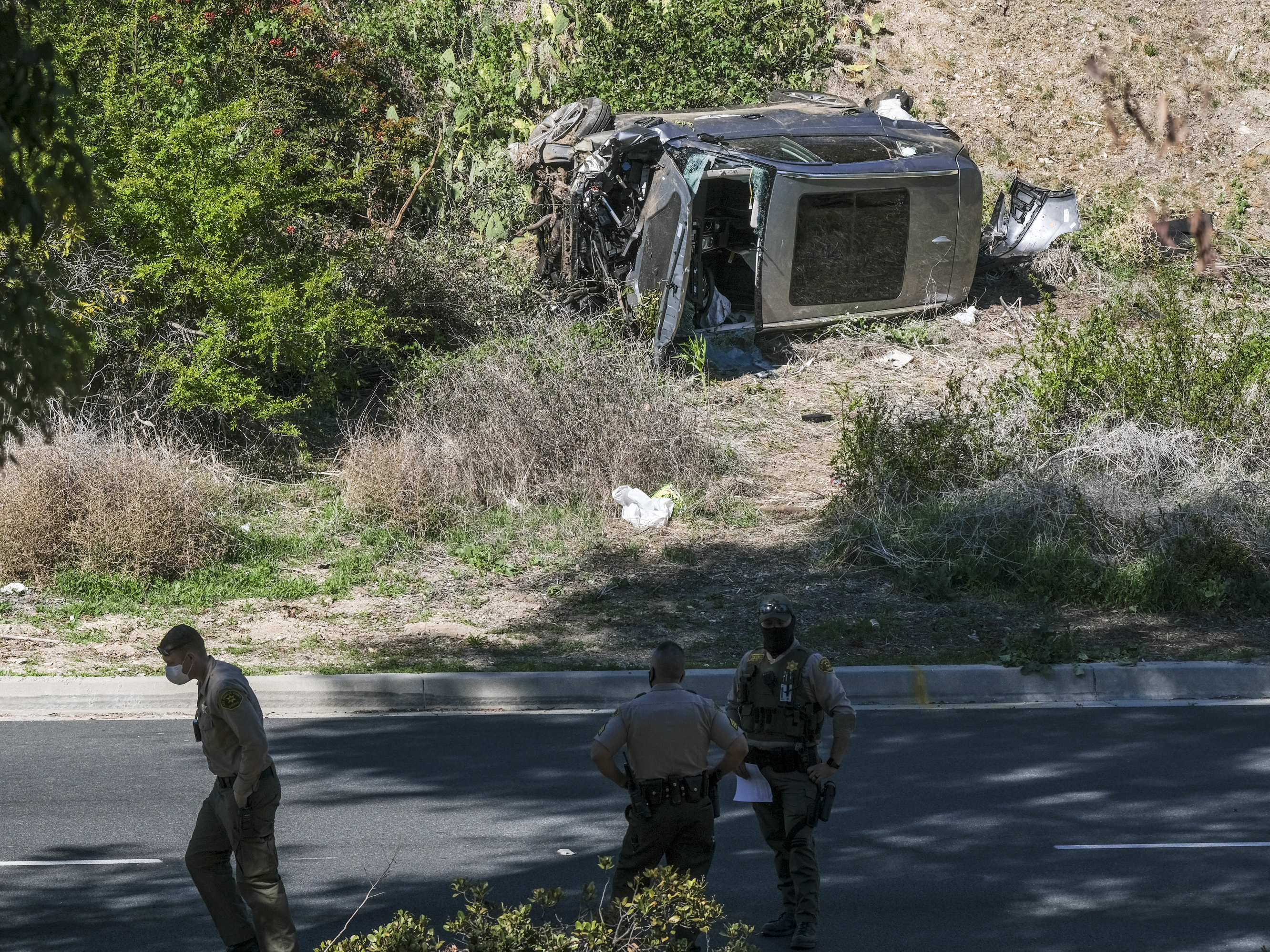 caption: A vehicle rests on its side after a rollover accident involving golfer Tiger Woods along a road in the Rancho Palos Verdes section of Los Angeles on Tuesday. Woods suffered leg injuries in the one-car accident and was undergoing surgery, authorities and his agent said.