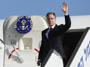 caption: U.S. Secretary of State Antony Blinken waves as he disembarks from an aircraft on his arrival in Tel Aviv, Israel, on Friday.