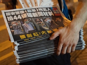 caption: A man buys multiple copies of the latest Apple Daily newspaper in Hong Kong. Police raided the office of Apple Daily, the city's fierce pro-democracy newspaper, in an operation involving more than 200 officers. Secretary for Security John Lee said the company used "news coverage as a tool" to harm national security, according to local media reports.