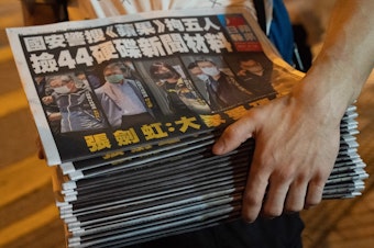 caption: A man buys multiple copies of the latest Apple Daily newspaper in Hong Kong. Police raided the office of Apple Daily, the city's fierce pro-democracy newspaper, in an operation involving more than 200 officers. Secretary for Security John Lee said the company used "news coverage as a tool" to harm national security, according to local media reports.