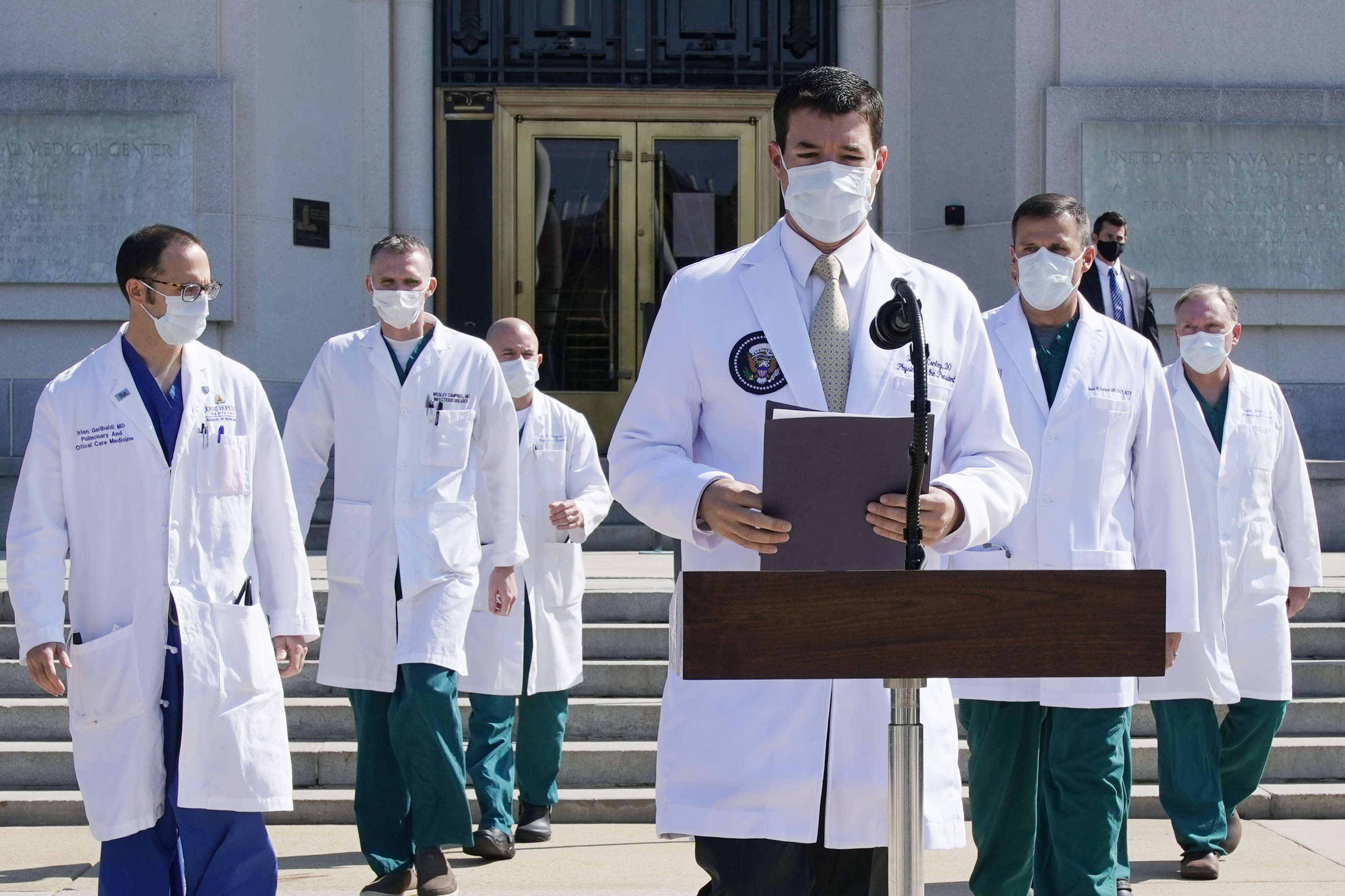 caption: Dr. Sean Conley, physician to President Donald Trump, and other doctors, arrive to brief reporters at Walter Reed National Military Medical Center in Bethesda, Md., Sunday, Oct. 4, 2020. Trump was admitted to the hospital after contracting the coronavirus. 