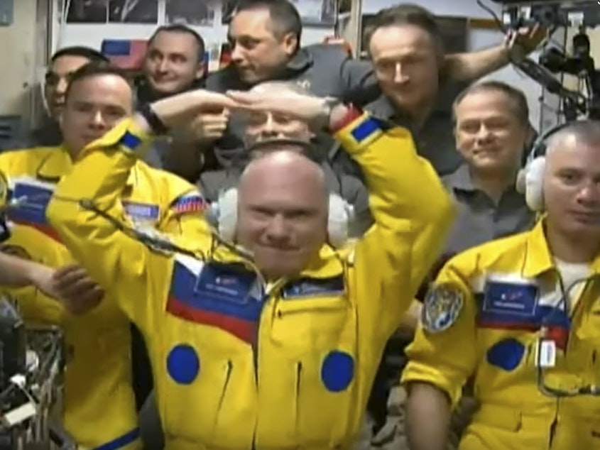 caption: In this photo taken from video footage released by the Roscosmos Space Agency, three Russian cosmonauts sport yellow spacesuits upon arriving on the International Space Station. A NASA astronaut now says it was not in support for Ukraine, but for the Russians' university school colors.