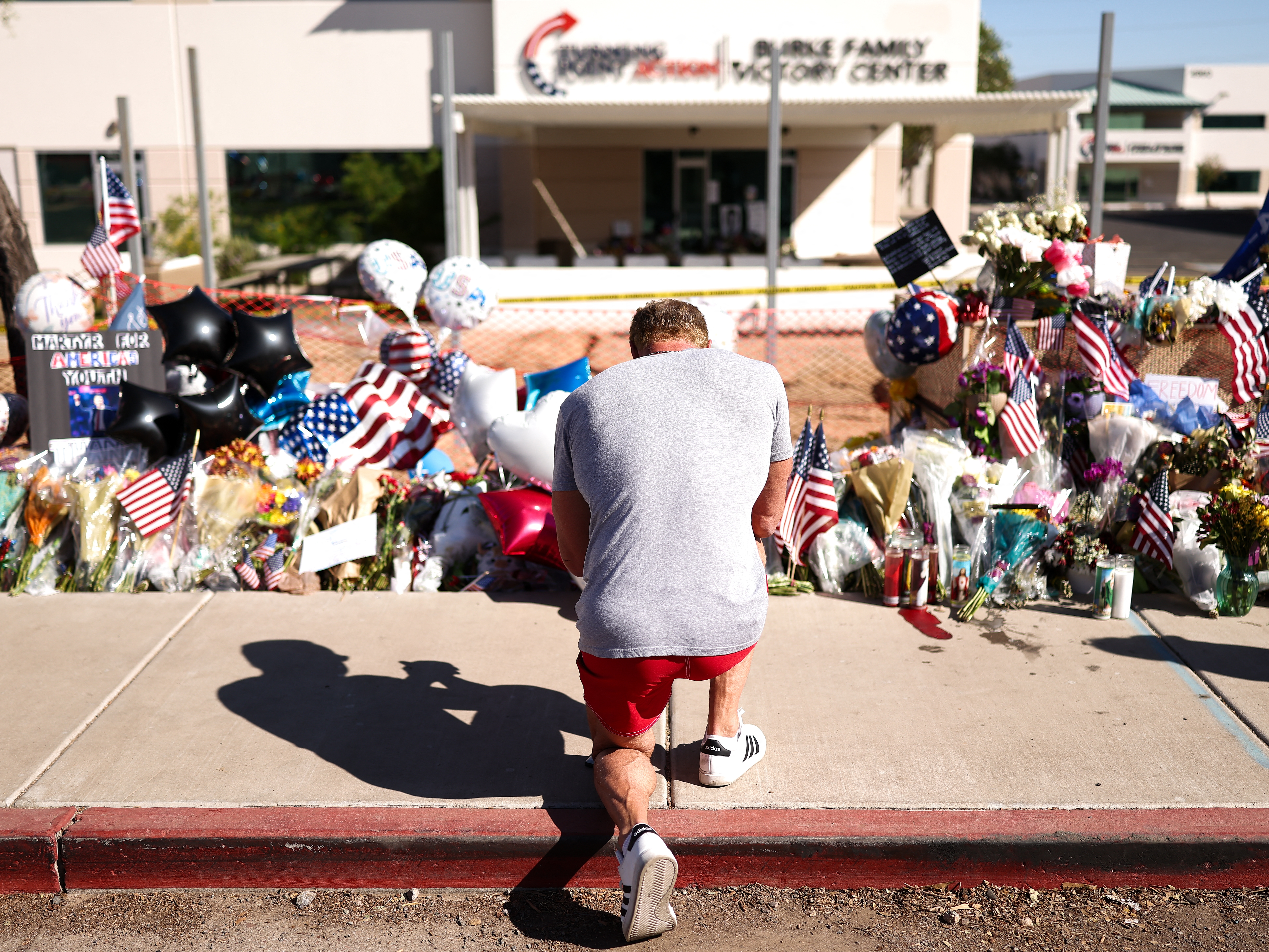 caption: People gather at a makeshift memorial for political activist and Turning Point USA Founder Charlie Kirk outside of the Turning Point USA headquarters in Phoenix, Ariz., on Sept. 14.