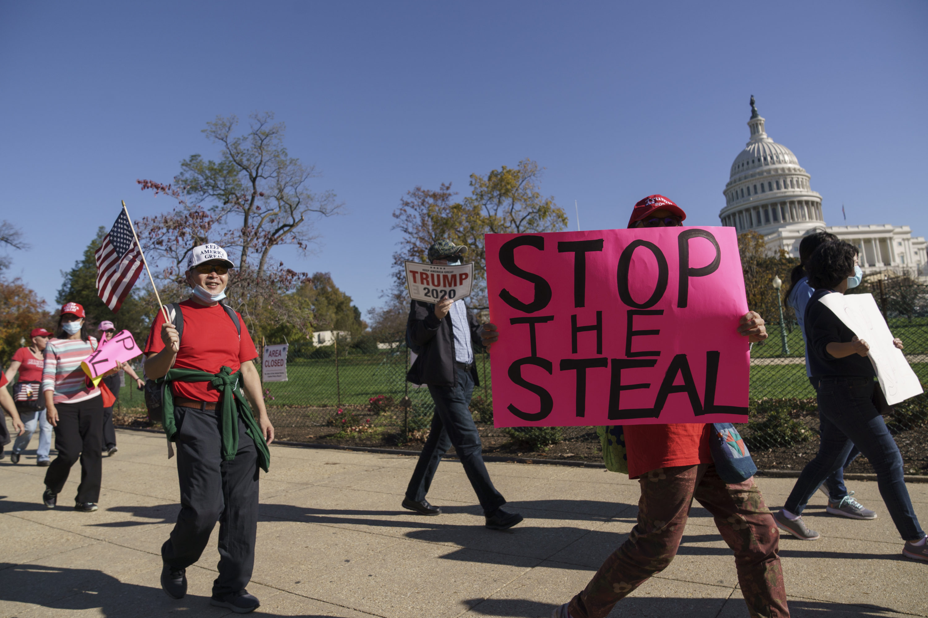 caption: Supporters of President Donald Trump carry flags and signs as they parade past the Capitol in Washington.  (AP Photo/J. Scott Applewhite)