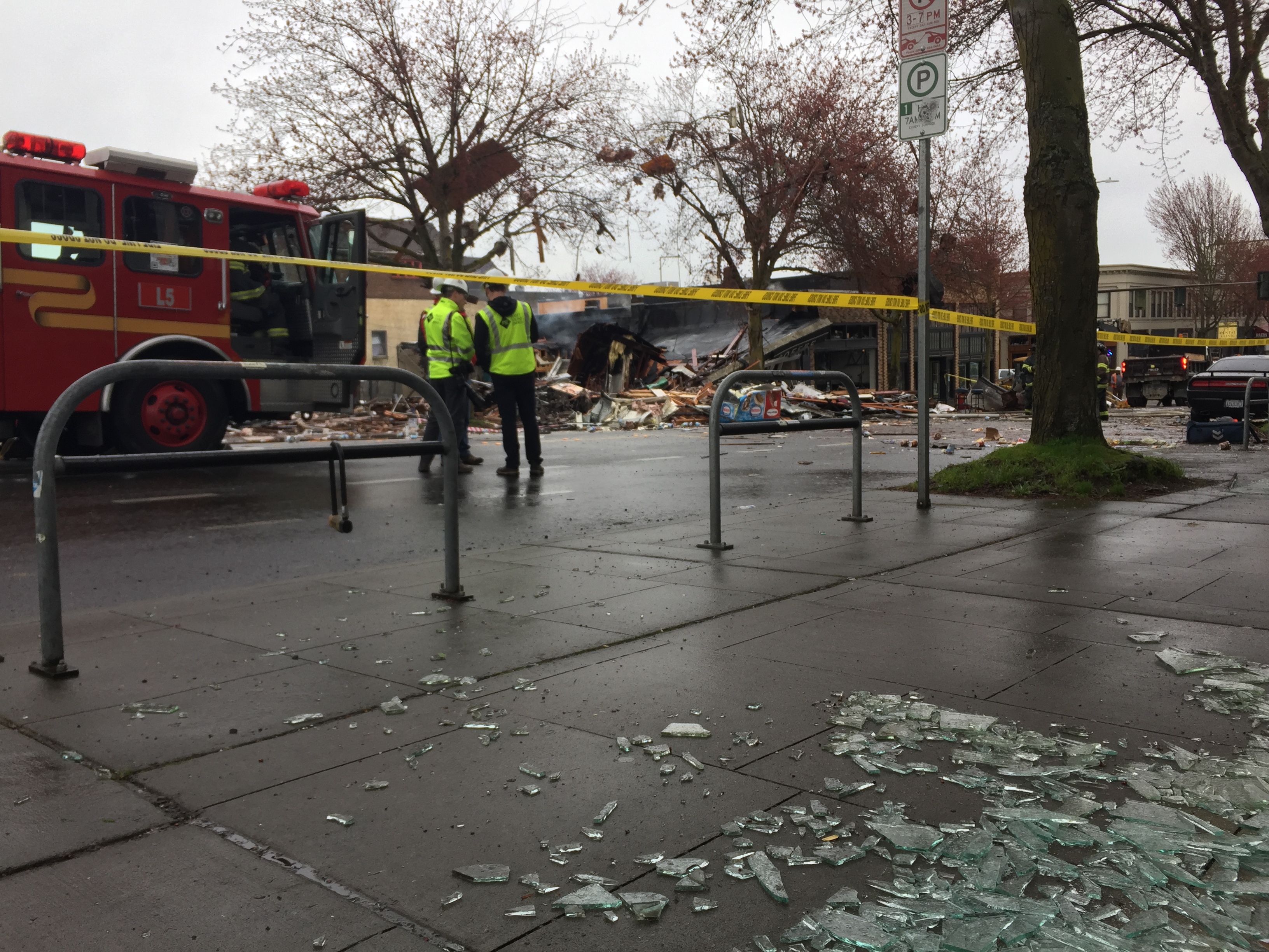 caption: Glass covers a sidewalk at the scene of a gas leak explosion in Seattle's Greenwood neighborhood in the early hours of Wed., March 9, 2016.