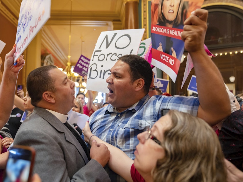 caption: Pastor Michael Shover of Christ the Redeemer Church in Pella, Iowa, left, argues with Ryan Maher, of Des Moines, as protesters clashed in the Iowa State Capitol rotunda, while the Iowa Legislature convened for a special session on July 11, 2023.