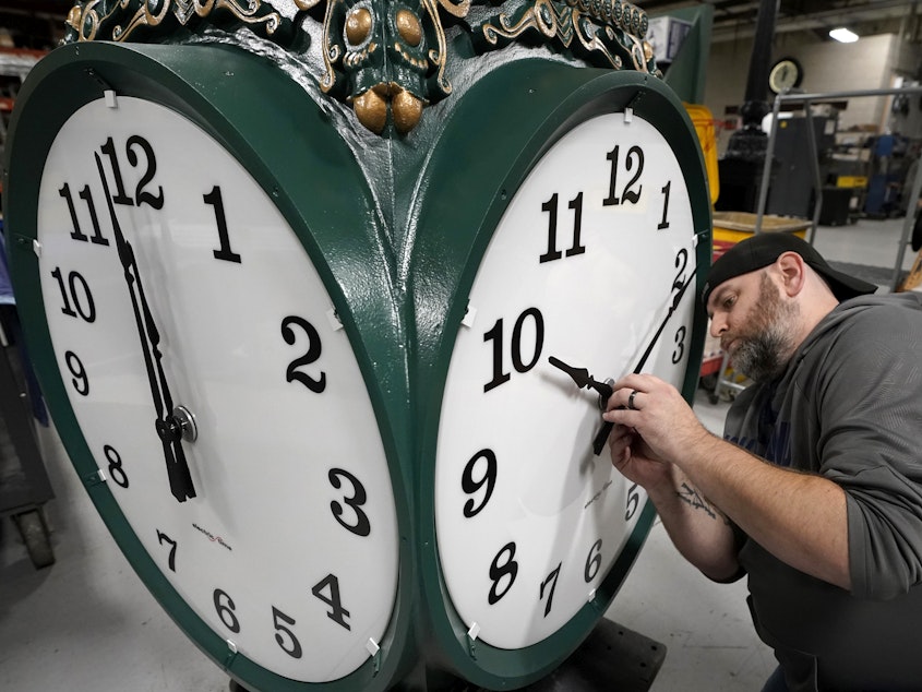 caption: A clock technician adjusts the hands on a large outdoor clock under construction at Electric Time Company in Medfield, Mass, last year, just days before daylight saving time was set to end.