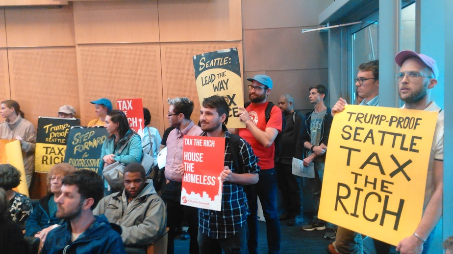 caption: Supporters of taxing the rich demonstrate at Seattle City Hall in June.