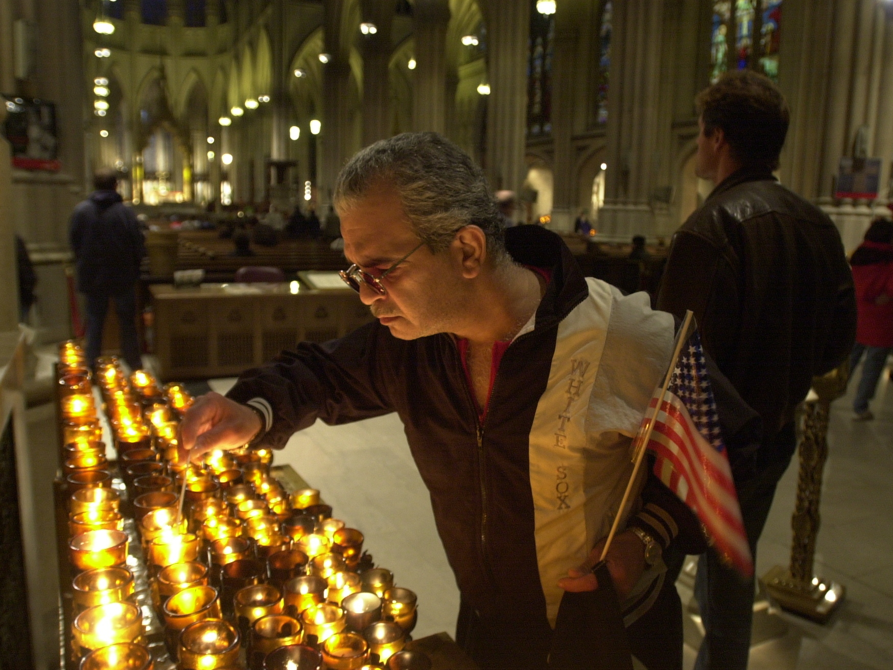 caption: A man lights a candle on Sept. 14, 2001 in memoriam of the victims of the September 11th terrorist attacks in New York City.