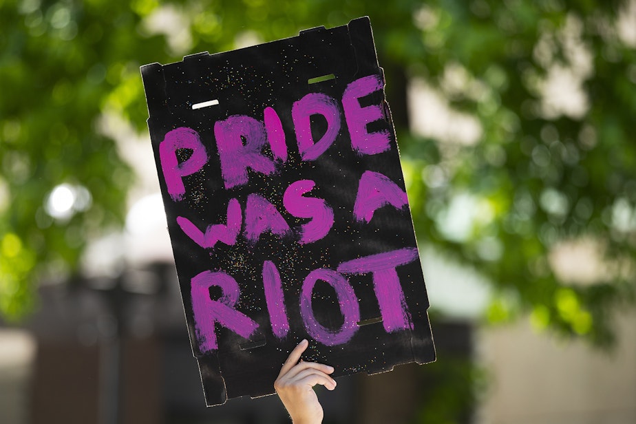 caption: "Pride was a riot," referring to the Stonewall Riots of 1969, reads a sign during the Seattle Pride Parade on Sunday, June 25, 2023, in downtown Seattle. 