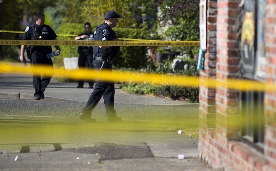 caption: Police officers investigate the scene of a shooting on Friday, May 10, 2019, at the intersection of East Union Street and 21st Avenue in Seattle.
