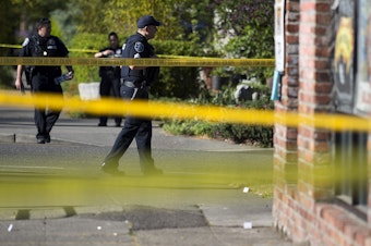 caption: Police officers investigate the scene of a shooting on Friday, May 10, 2019, at the intersection of East Union Street and 21st Avenue in Seattle.