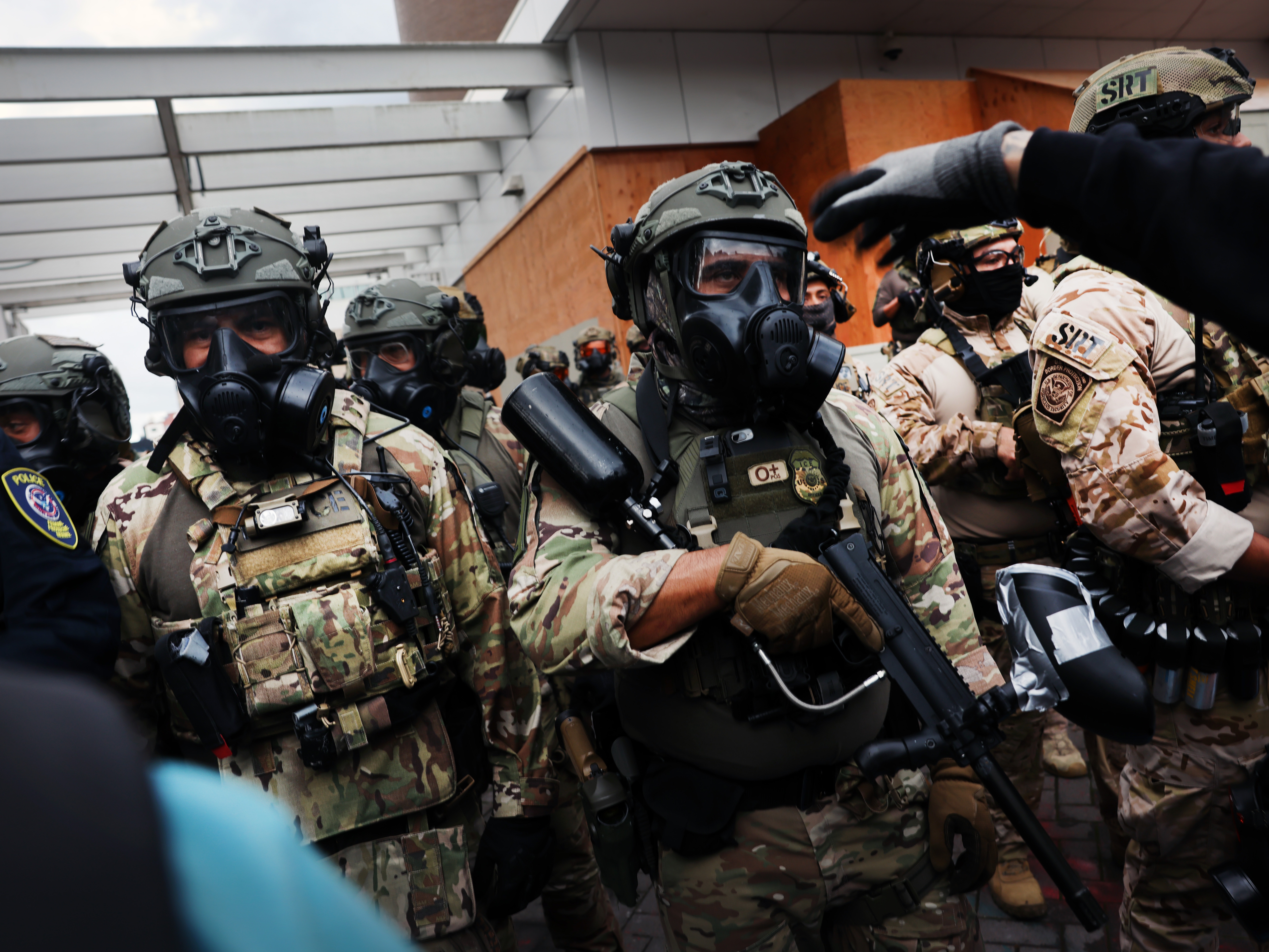caption: Federal law enforcement officials and police attempt to keep protesters back outside a U.S. Immigration and Customs Enforcement facility in Portland, Ore., on Saturday. Oregon's governor said California National Guard members had arrived in Oregon.