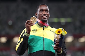 caption: Gold medalist Hansle Parchment of Jamaica holds up his medal on the podium during the medal ceremony for the men's 110-meter hurdles on Aug. 5.