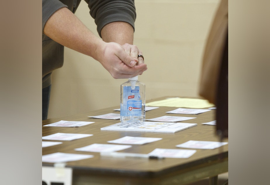 caption: A Michigan voter uses hand sanitizer that the polling place provided after casting his ballot at Warren Woods Baptist Church in Warren, Mich., last week.