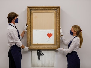 caption: Banksy's "Love is in the Bin" is installed at Sotheby's on September 03, 2021 in London, England.
