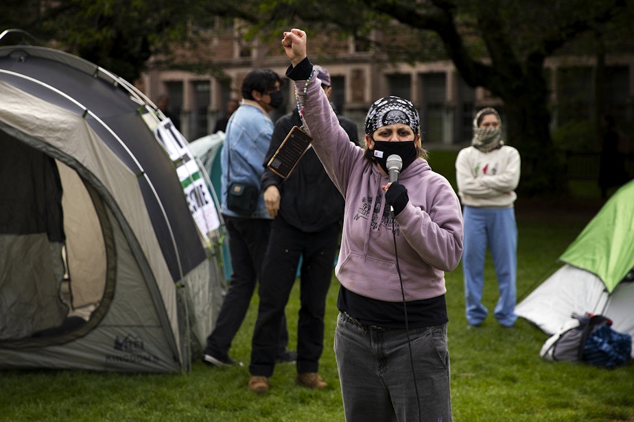 caption: University of Washington alumni Gemini Gnull, with Freedom Road Socialist Organization, leads a chant as students set up what they are calling the UW Palestine Encampment on Monday, April 29, 2024, on the University of Washington campus in Seattle. 