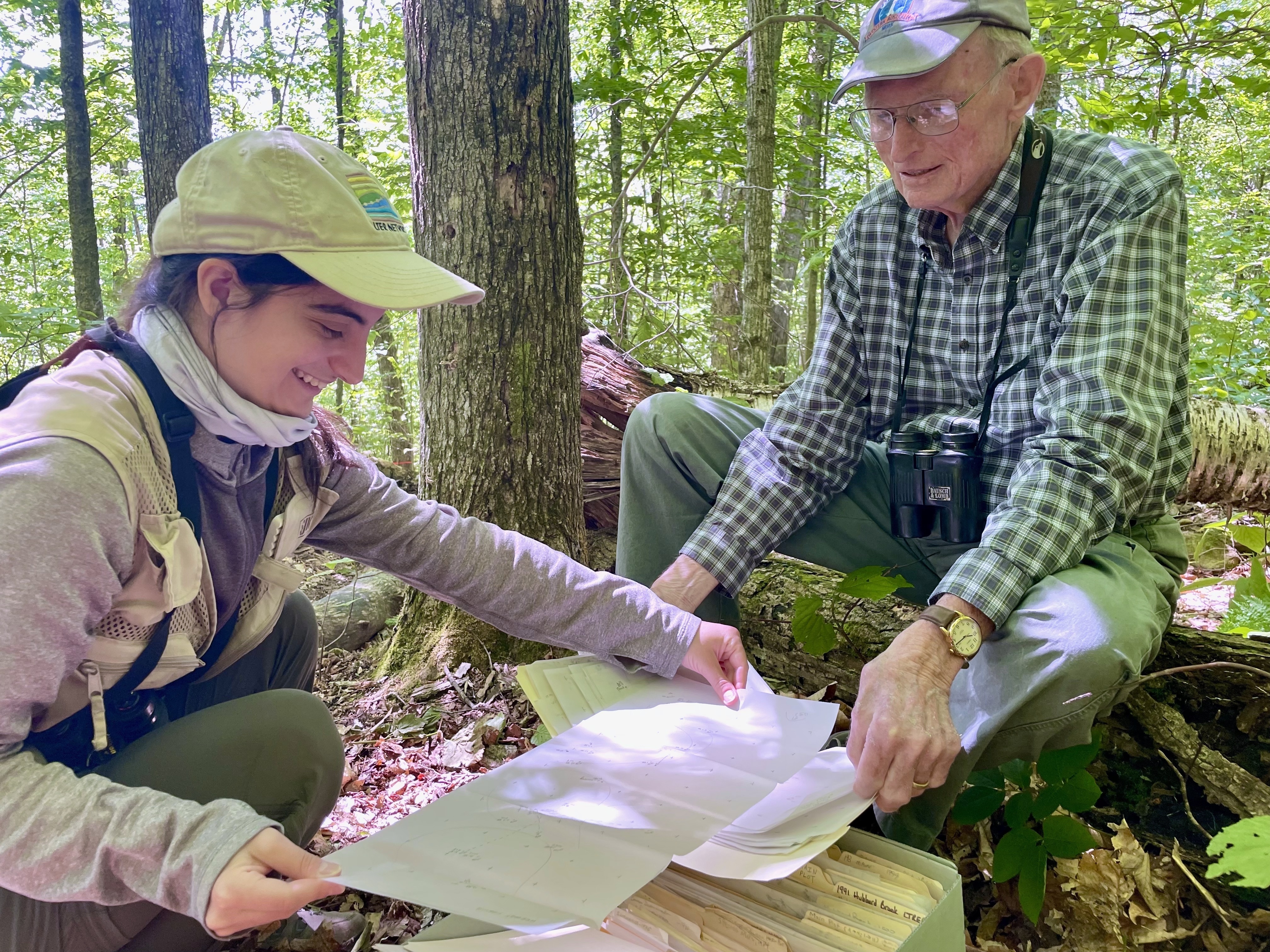 caption: Miranda Zamarelli and Dick Holmes of Dartmouth College review one of the early paper maps used to chart songbird territories in a patch of woods in central New Hampshire.